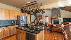 A spacious kitchen with wooden cabinets, a stainless steel refrigerator, and a hanging pot rack. - Beautiful 4-bedroom house in Granby perfect for your getaway (Granby)