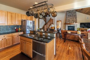 A spacious kitchen with wooden cabinets, a stainless steel refrigerator, and a hanging pot rack. - Beautiful 4-bedroom house in Granby perfect for your getaway (Granby)