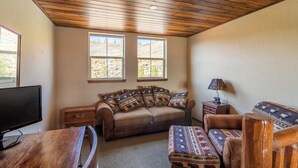 A cozy living room with a sofa, ottoman, and a television on a wooden table. - Beautiful 4-bedroom house in Granby perfect for your getaway (Granby)