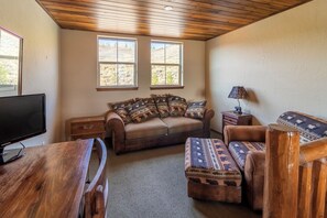 A cozy living room with a sofa, ottoman, and a television on a wooden table. - Beautiful 4-bedroom house in Granby perfect for your getaway (Granby)