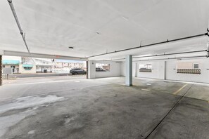 Eine leere Parkgarage mit Betonböden und -wänden, einigen Säulen und einem sichtbaren Ausgangsschild.