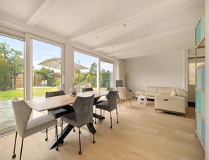 A spacious dining area with a large table and chairs, a sofa, and a view of the outdoors. - Modern Eco Home Sint Maartenszee (Sint Maartensvlotbrug)