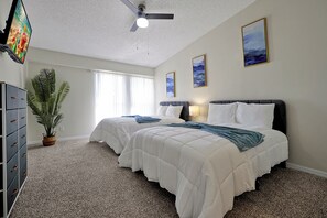 A hotel room with two beds, a ceiling fan, a TV, a potted plant, and artwork on the walls. - Welcoming 2-bedroom apartment with AC in Orlando (Orlando)