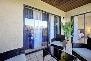 Ein Balkon mit Korbmöbeln, einer Topfpflanze und Blick auf ein Gebäude.