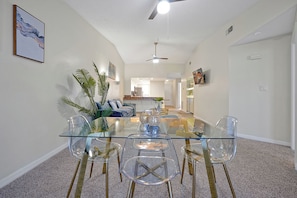 A dining area with a glass table and chairs, a ceiling fan, and a kitchen in the background. - Welcoming 2-bedroom apartment with AC in Orlando (Orlando)
