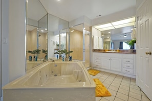 A modern bathroom with a large bathtub, a walk-in shower, and a vanity with a mirror. - Welcoming 2-bedroom apartment with AC in Orlando (Orlando)