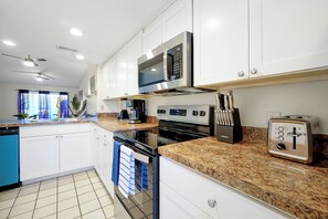 A modern kitchen with white cabinets, a stainless steel microwave, an oven, a toaster, and a coffee maker. - Welcoming 2-bedroom apartment with AC in Orlando (Orlando)