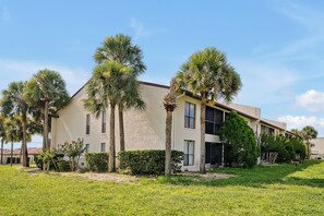 A two-story building with a flat roof and a beige exterior. There are palm trees and a well-maintained lawn in front. - Welcoming 2-bedroom apartment with AC in Orlando (Orlando)