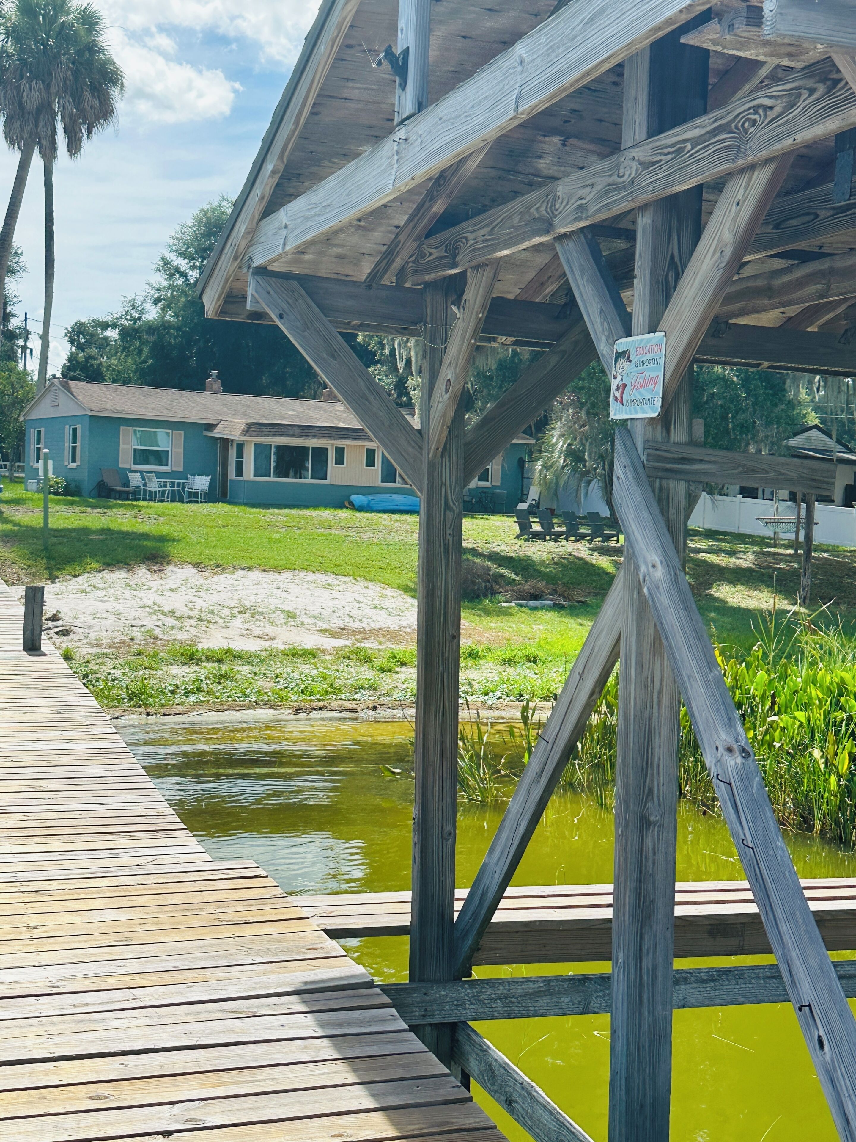 A wooden dock leading to a covered area with a sign indicating fishing importance.