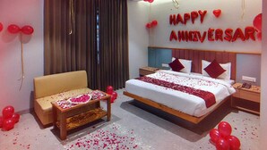 A hotel room with a bed, a sofa, and a small table with a heart-shaped decoration. - Hotel Castillo Inn (Jaipur)