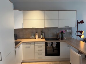A modern kitchen with white cabinets, a black countertop, and a built-in oven.