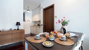 Eine moderne Küche mit einem Esstisch, gedeckt für das Frühstück, mit Eiern, Obst und Getränken.