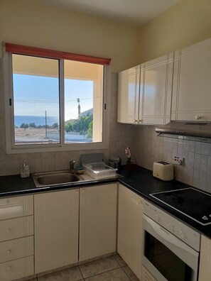 Una cocina con ventana, armarios blancos, un lavamanos, un tostador y un horno.