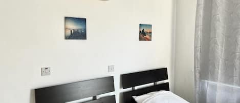 Une chambre avec deux lits, un climatiseur et deux tableaux accrochés au mur.