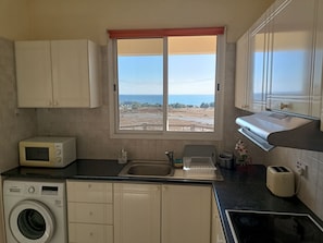 A compact kitchen with a washing machine, microwave, and toaster. - MOLOS Complex  (Pafos)