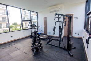 A gym with exercise equipment, large windows, and a view of buildings. - Suite fourth floor pool view Downtown Punta Cana (Punta Cana)