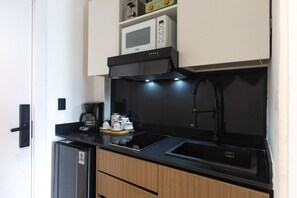 A compact kitchenette with a microwave, coffee maker, and a sink. - Suite fourth floor pool view Downtown Punta Cana (Punta Cana)