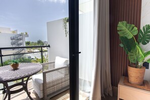 Ein Balkon mit einem Korbstuhl, weißen Kissen und einem Topfpflanzen.
