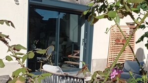 A building with a cross on the wall, a covered outdoor seating area, and a gravel ground. - Charming vacation rental with a jacuzzi/spa—Anjou (castles), countryside, river, hiking (Étriché)