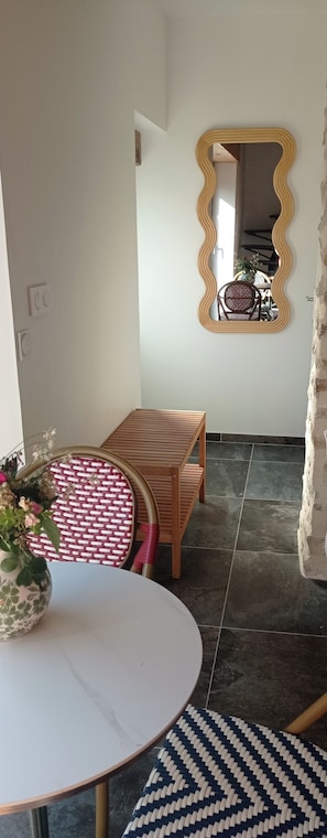 A dining area with a round table, chairs, a mirror, and a potted plant.