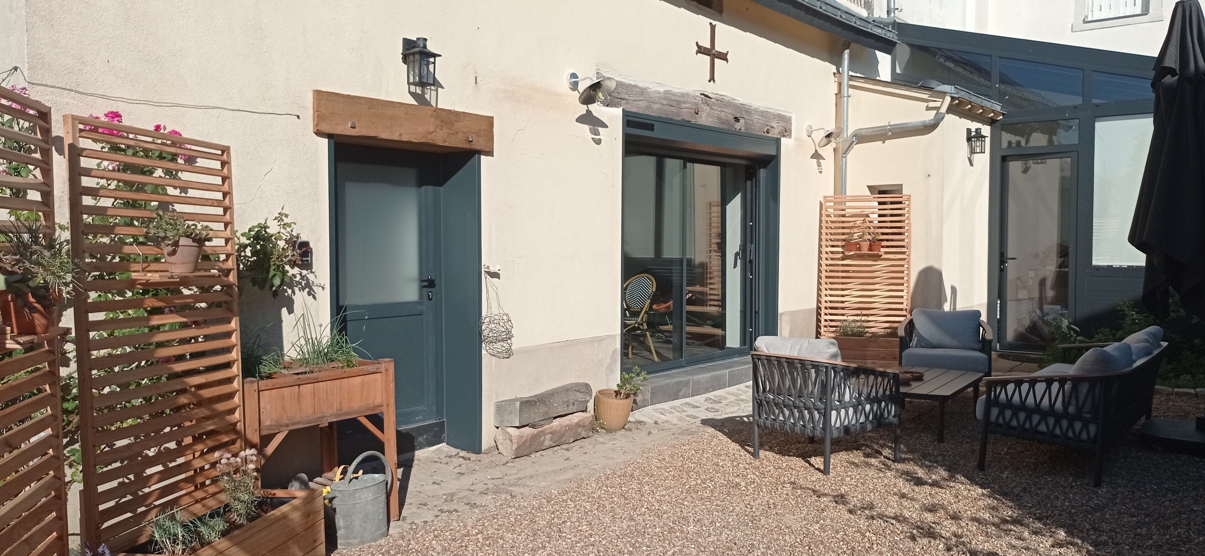A patio area with a wooden fence, a door, a chair, and a table.