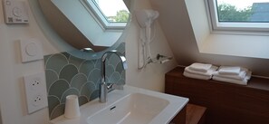 A modern bathroom with a skylight, a built-in sink, a hairdryer, and a towel rack.