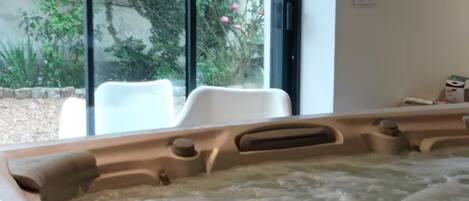 A hot tub with a view of pink flowers through a glass door.