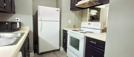 Cocina compacta con refrigerador, microondas, estufa y horno.