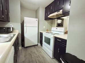 A compact kitchen with a refrigerator, microwave, stove, and oven. - Sun Harbor Overlook - Sleeps 4 - 1 Bedroom Condo - Waterfront View (Panama City)