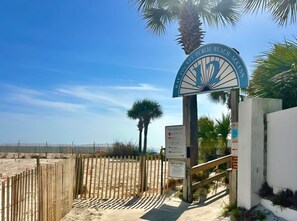 A beach entrance gate with a sign reading 'County Public Beach Access' and a palm tree in the background. - Two Bed, Two Bath Townhouse | Sleeps 8 | Community Pool | No Additional Fees (Panama City)