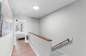 A hallway with a wooden floor, a white wall, and a ceiling light. - Two Bed, Two Bath Townhouse | Sleeps 8 | Community Pool | No Additional Fees (Panama City)