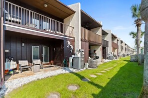 A modern hotel with a covered outdoor seating area, a pool, and a well-maintained lawn. - Two Bed, Two Bath Townhouse | Sleeps 8 | Community Pool | No Additional Fees (Panama City)