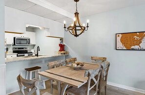A modern kitchen with white cabinets, a microwave, and a stove. There is a dining table with chairs and a chandelier above. - Two Bed, Two Bath Townhouse | Sleeps 8 | Community Pool | No Additional Fees (Panama City)