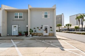 A two-story building with a flat facade, a front door, and a small porch area with potted plants. - Two Bed, Two Bath Townhouse | Sleeps 8 | Community Pool | No Additional Fees (Panama City)