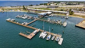 A marina with multiple docks and boats, connected to a coastal area with buildings and a clear sky. - Sun Harbor Serenity - Sleeps 4 - 1 Bedroom Condo Ground Floor Unit (Panama City)