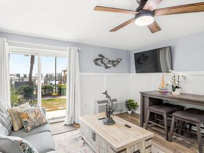 A modern living room with a sofa, coffee table, and a dining area with stools. - Sun Harbor Serenity - Sleeps 4 - 1 Bedroom Condo Ground Floor Unit (Panama City)
