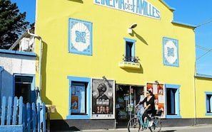 A yellow building with the sign 'LIMEDA DES AMILES' and a poster advertising a design competition. - Family Home in Groix – Sleeps 8 – Garden & Bikes (Groix)