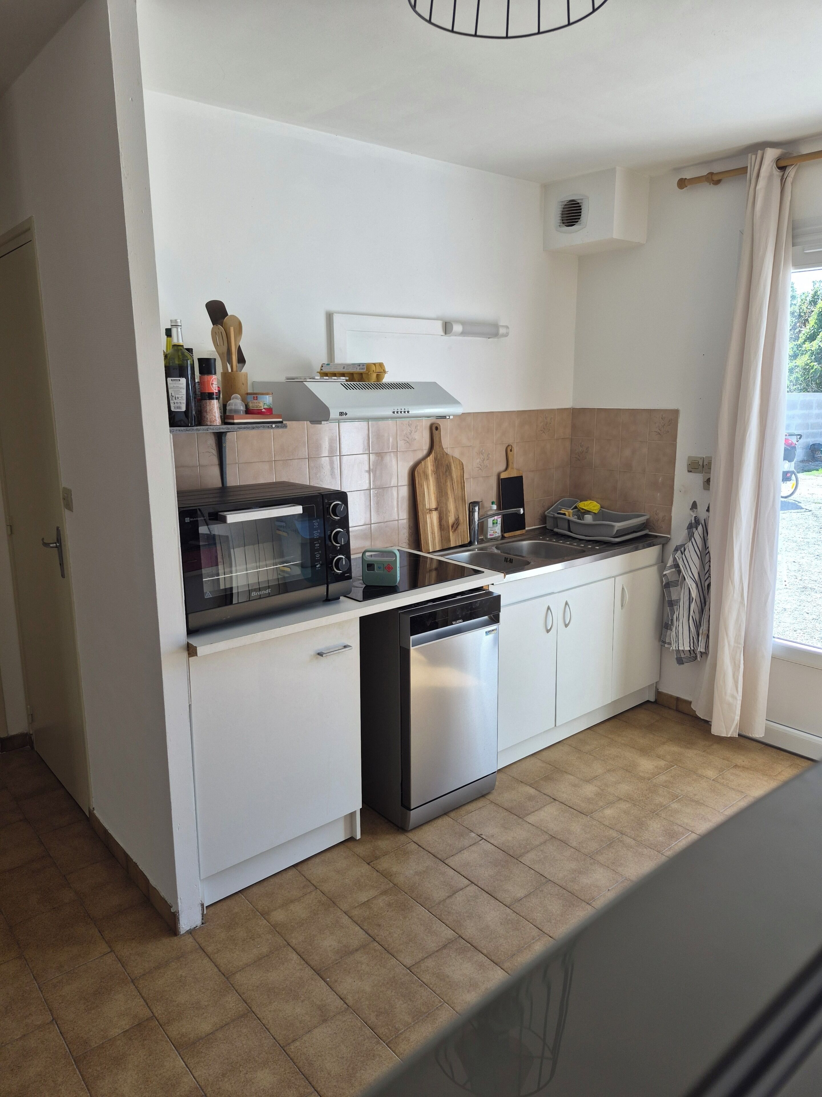 A compact kitchen with a built-in microwave, toaster, and dishwasher.