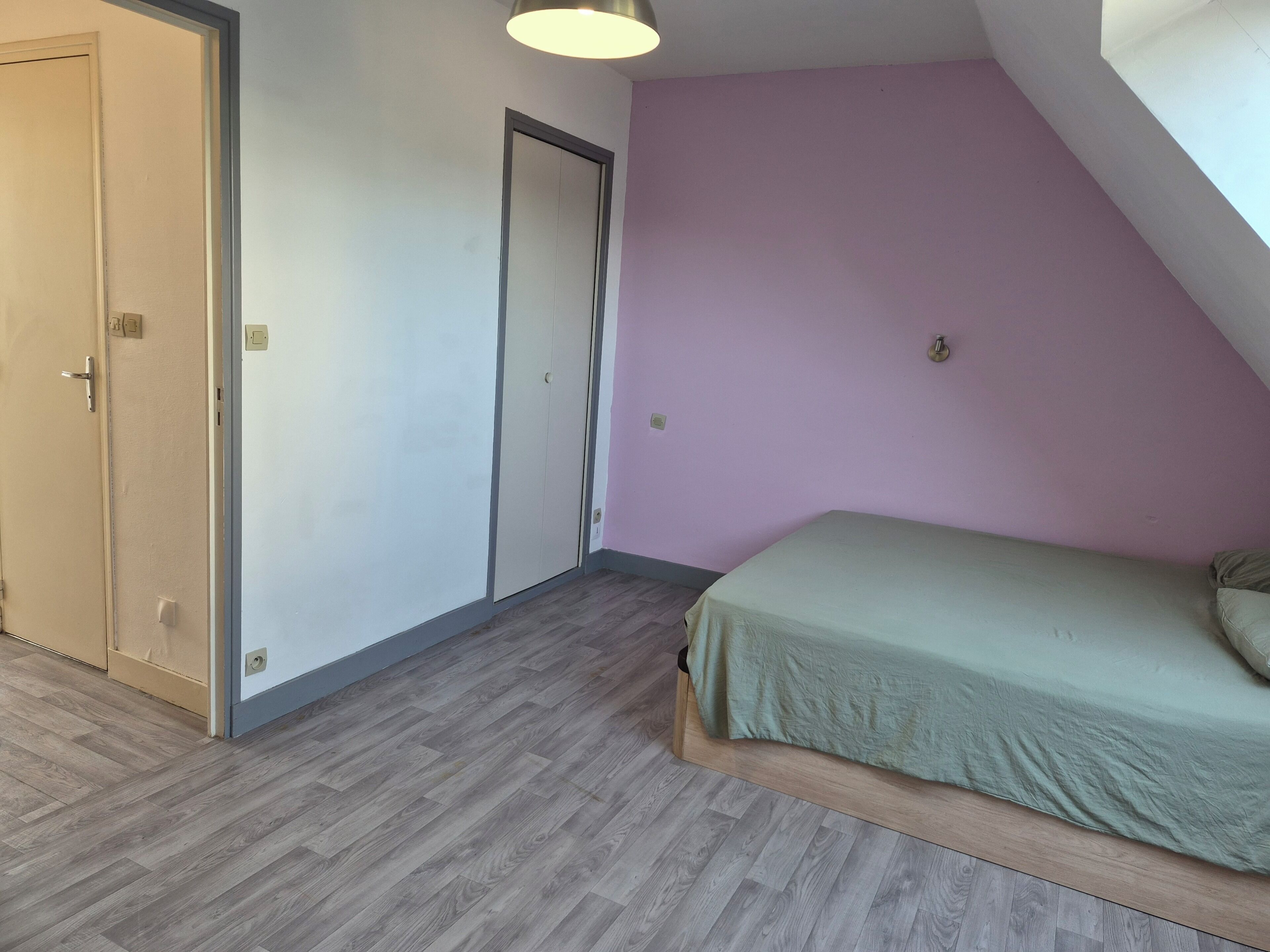 A bedroom with a bed, a door, and a light fixture.
