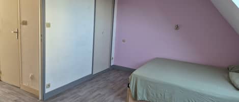 Een slaapkamer met een bed, een deur en een lamp.
