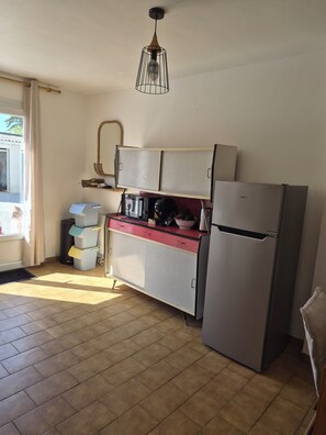 A kitchen with a refrigerator, a stove, and a hanging light fixture. - Family Home in Groix – Sleeps 8 – Garden & Bikes (Groix)