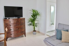 A living room with a wooden cabinet, a television, a potted plant, and a grey sofa with cushions. - Puerto de la Cruz: Amazing Penthouse with Ocean Views (Puerto de la Cruz)