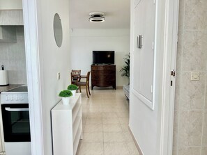 A modern kitchen with a stove, a dining area with a table and chairs, a TV, and a cabinet. - Puerto de la Cruz: Amazing Penthouse with Ocean Views (Puerto de la Cruz)