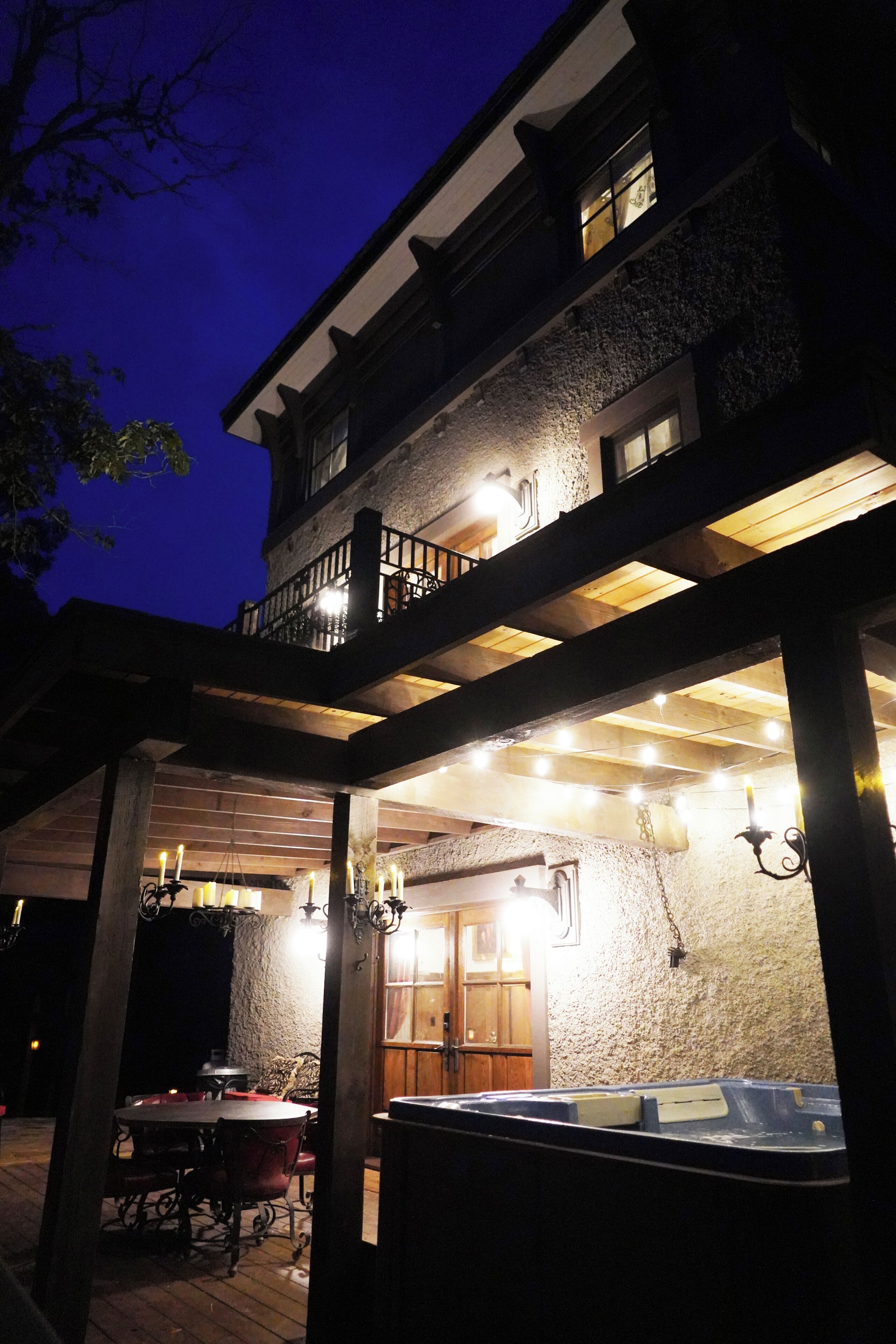 A building with a covered outdoor area, a hot tub, and a dining table with chairs.
