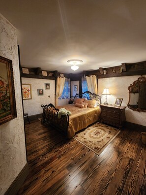 A bedroom with a wooden floor, a bed with a gold bedspread, a nightstand with a lamp, and a dresser. - Family friendly castle, 17th century archaic chateau, providing all amenities. (Franklin)