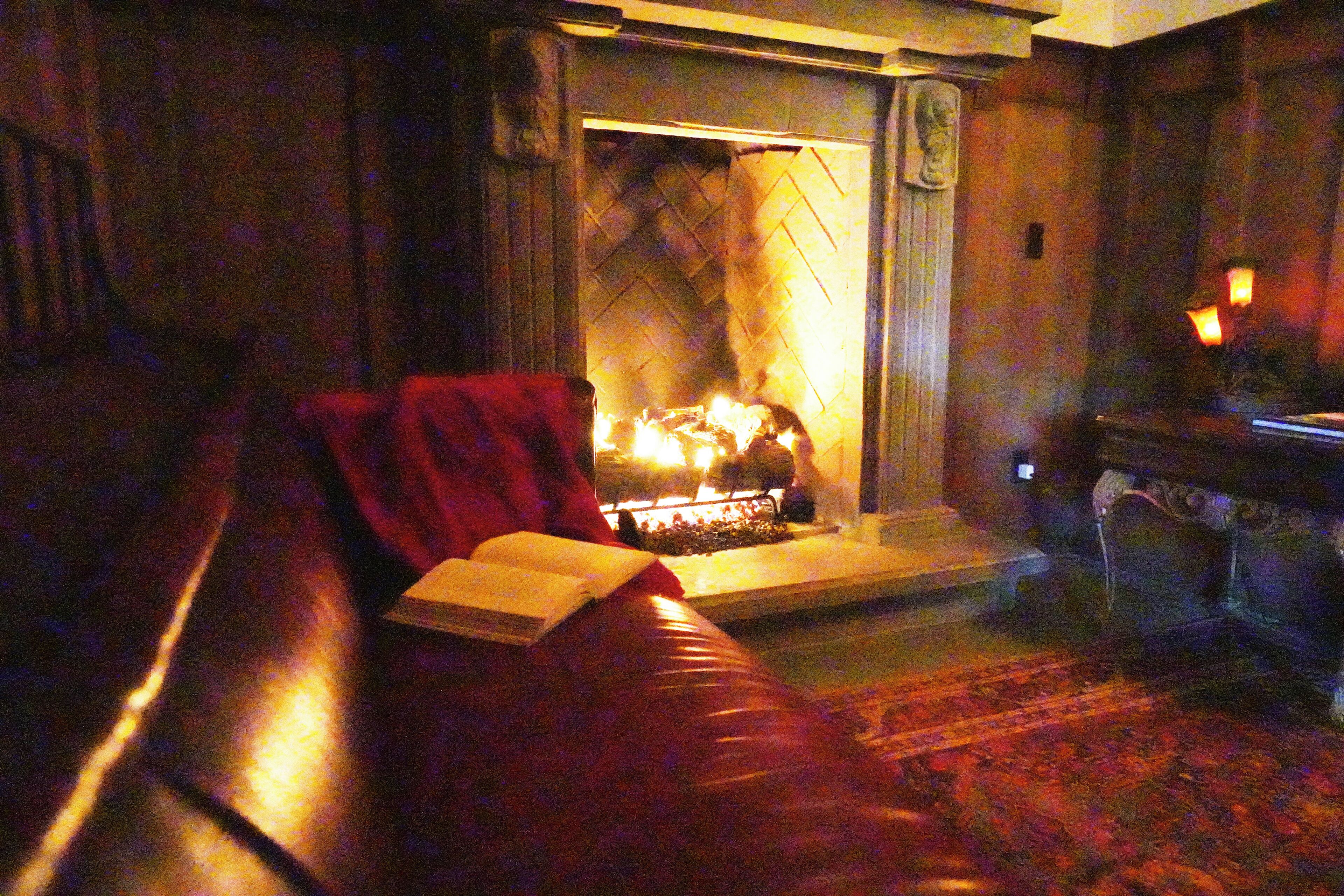 Una sala acogedora con chimenea, un sofá de cuero rojo y un libro sobre la mesa.