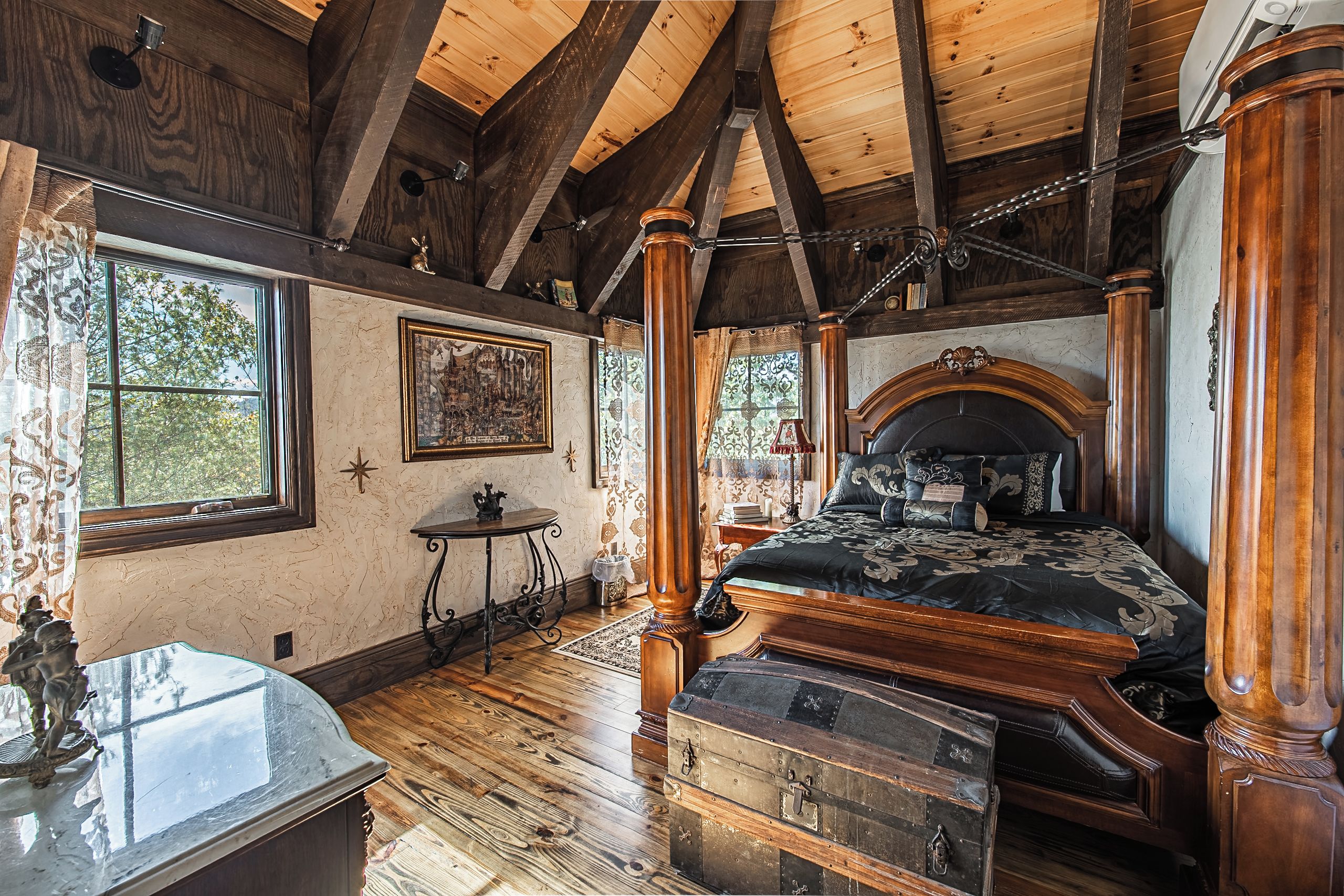 Un dormitorio con una cama grande, vigas de madera, un ventanal y un aparador.
