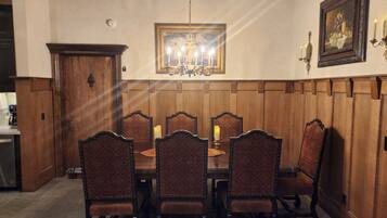 A dining room with a wooden paneled wall, a chandelier, and a framed painting.