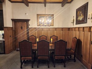 A dining room with a wooden paneled wall, a chandelier, and a framed painting. - Family friendly castle, 17th century archaic chateau, providing all amenities. (Franklin)