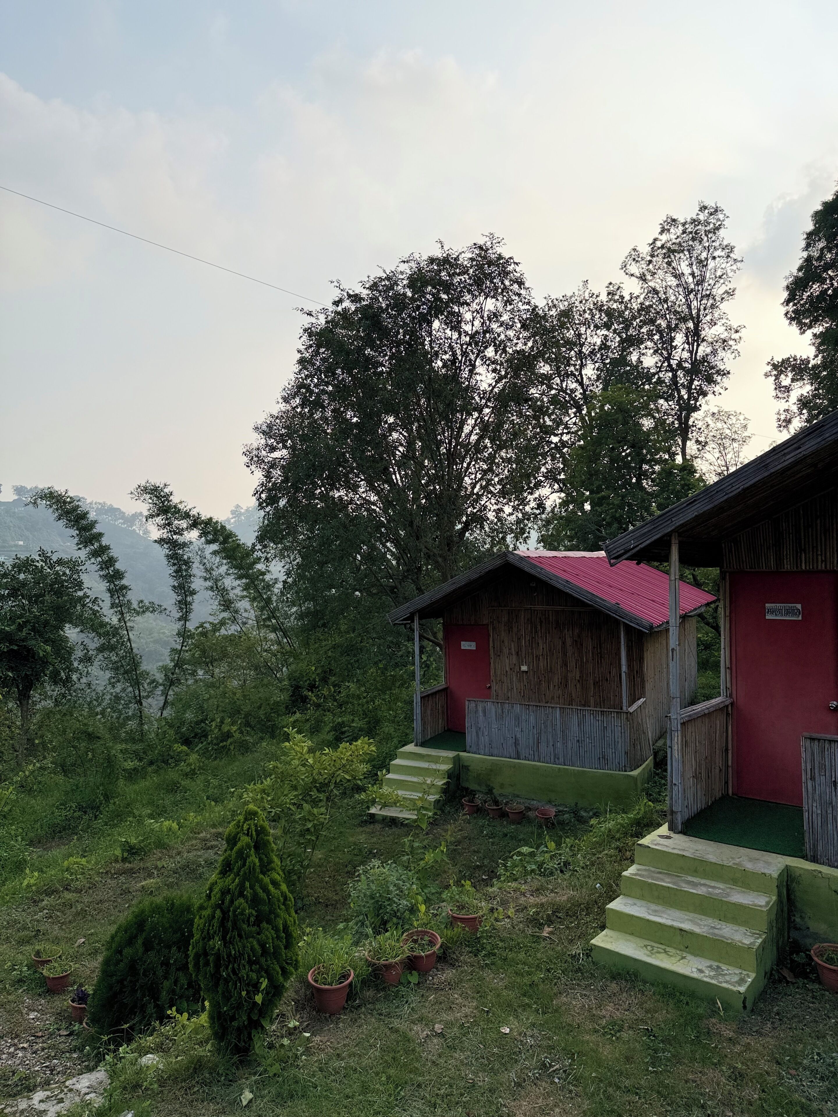 Eine rustikale Holzhütte mit rotem Dach, umgeben von üppigem Grün und Bäumen.